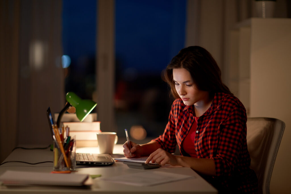 people education freelance learning concept student girl with notebook calculator doing math home night